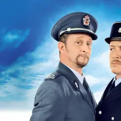 Dwóch policjantów w mundurach na tle błękitnego nieba z chmurami. Wyglądają, jakby mieli nic do zgłoszenia.