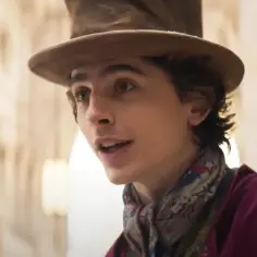 Młody Willy Wonka w kapeluszu i kolorowym szaliku, zapowiadający film "Charlie i fabryka czekolady 2023".