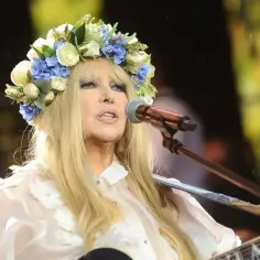 Maryla Rodowicz w wianku śpiewa swoje utwory, grając na gitarze.