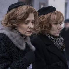 Dwie kobiety w czapkach i eleganckich płaszczach, być może na pogrzebie, w scenie z "Stulecie Winnych sezon 5".