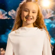 Uśmiechnięta dziewczynka z brokatem na powiekach, gotowa na występy na Eurowizji Junior.