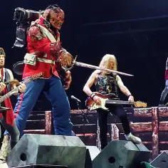 Iron Maiden w Warszawie: Bruce Dickinson z flagą, Eddie w mundurze i muzycy grający na gitarach.