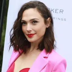 Gal Gadot w różowej marynarce i czerwonym topie, promuje swoje filmy.