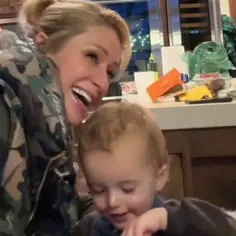 Paris Hilton z dziećmi, śmieje się radośnie, podczas gdy jej syn bawi się na stole.