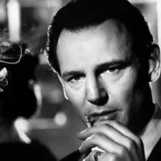 Liam Neeson jako Oskar Schindler, z papierosem w dłoni, w kadrze z filmu "Lista Schindlera".