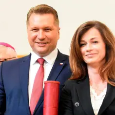 Katarzyna Czarnek, której wiek jest nieznany, uśmiecha się obok mężczyzny w garniturze. W tle widać biskupa.
