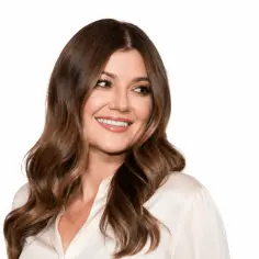 Uśmiechnięta Marta Surnik, której mąż jest dumny z jej piękna, prezentuje swoje lśniące włosy i elegancką bluzkę.