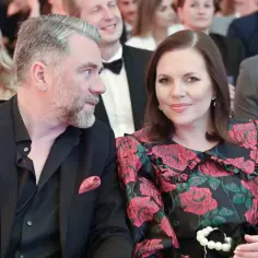 Kuba Badach z żoną, z uśmiechem patrzą na siebie. W tle widać innych gości.