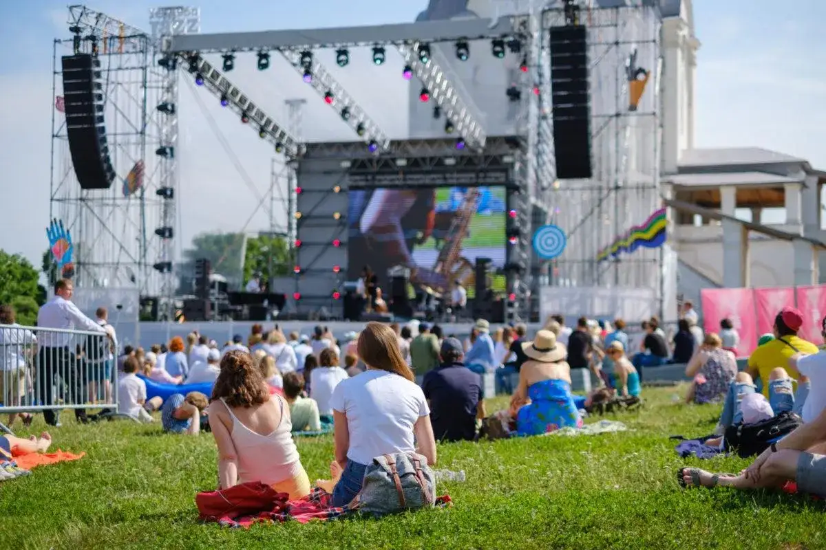 Widownia na trawie przed sceną, gdzie trwa koncert. W tle wielki ekran i rusztowania. To część eska music tour.
