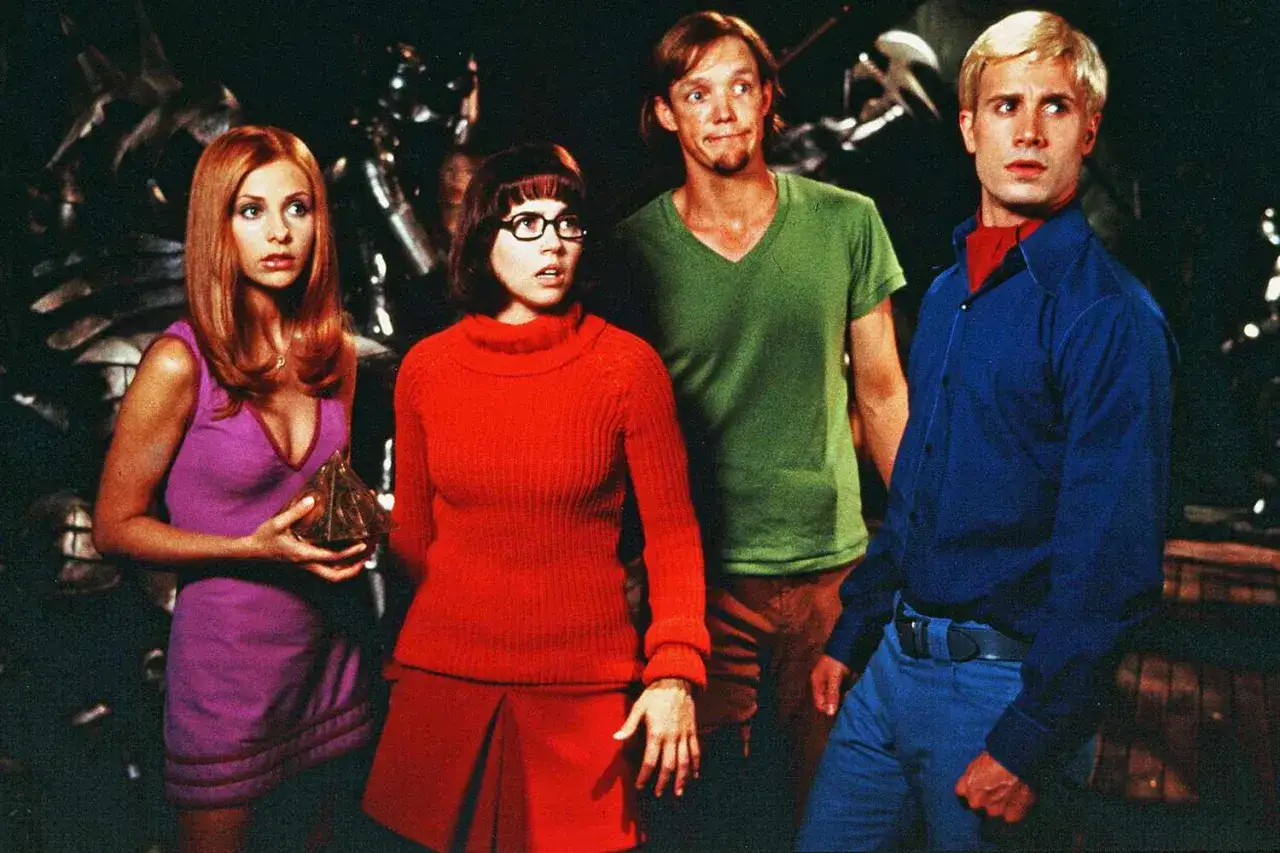 Obsada filmu Scooby-Doo: Daphne, Velma, Shaggy i Fred w swoich charakterystycznych strojach, gotowi na kolejną zagadkę.