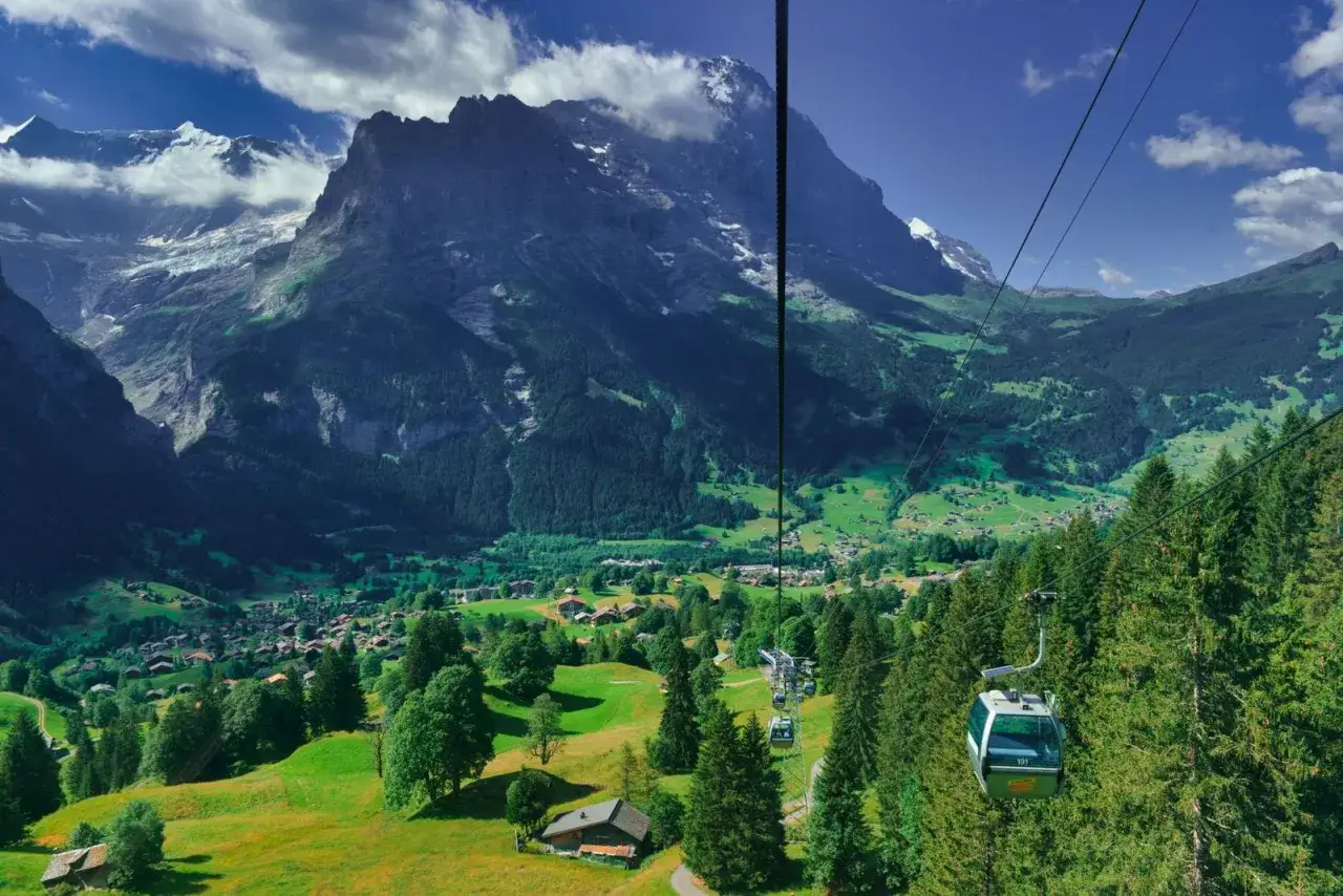Widok z kolejki linowej na malowniczą dolinę Grindelwald, otoczoną majestatycznymi szczytami Alp.