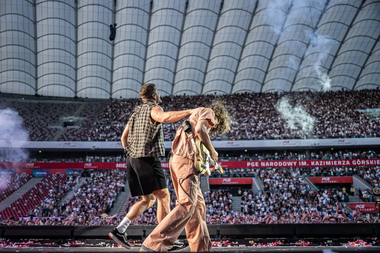 Imagine Dragons koncert na PGE Narodowym. Dwóch muzyków na scenie, tłumy fanów, dym i światła.