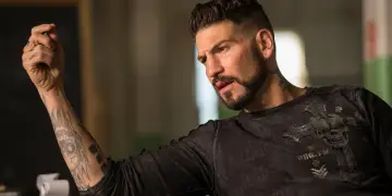 Jon Bernthal z tatuażami na ręce i szyi, w ciemnej koszulce z czaszką. Wiele jego filmów i seriali to hity.