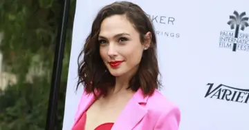 Gal Gadot w różowej marynarce i czerwonym topie, promuje swoje filmy.