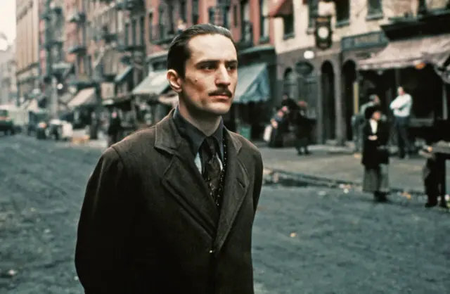 Robert De Niro w kultowych rolach. Młody Vito Corleone na ulicach Nowego Jorku w jednym z jego niezapomnianych filmów.